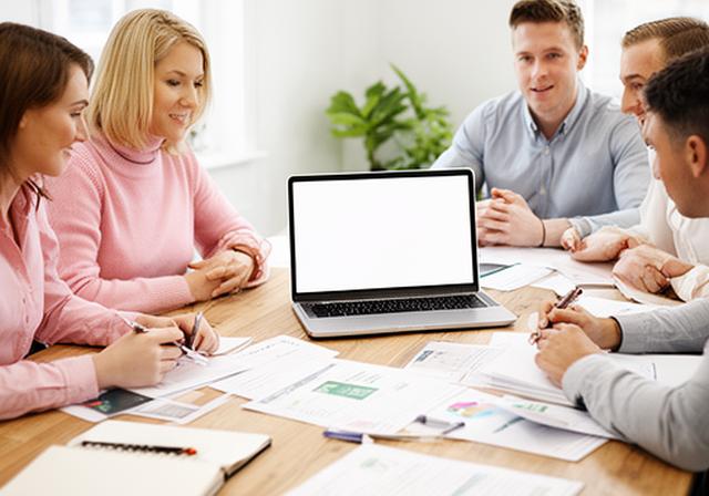 The A1 Leinster Valuations team in a bright Dublin office discussing business exit planning resources with a laptop on a wooden table